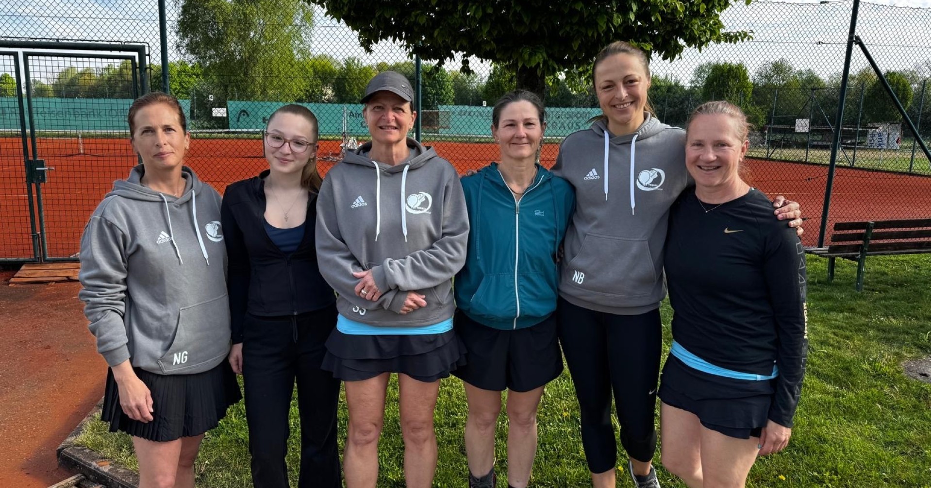Damen-Tennismannschaft auf Tennisplatz im Freien vor Baum und Netz