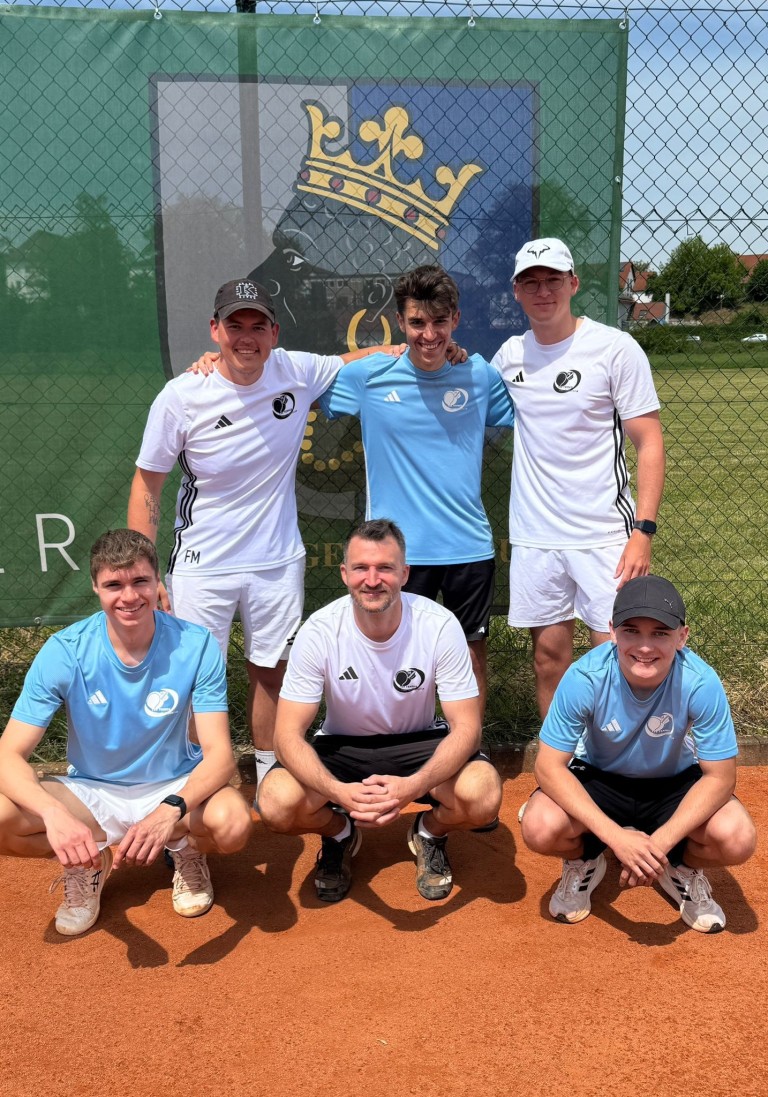 Tennismannschaft posiert auf Sandplatz vor Vereinswappen im Sommer