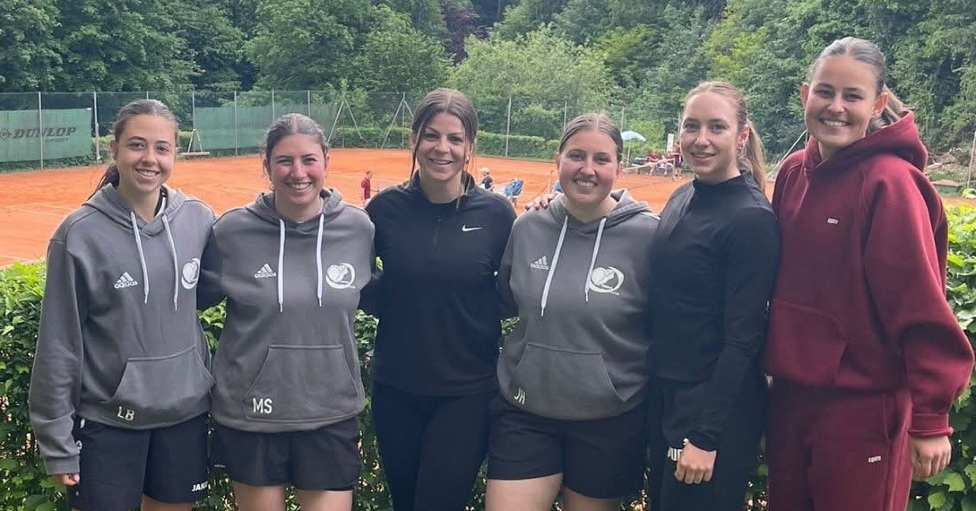 Gruppenfoto eines Damen-Tennisteams vor einem Tennisplatz im Freien