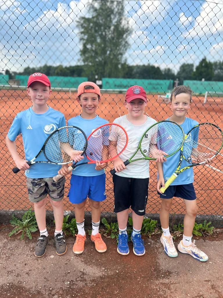 Vier Jungen mit Tennisschlägern auf einem Tennisplatz, Gruppenfoto beim Tennistraining
