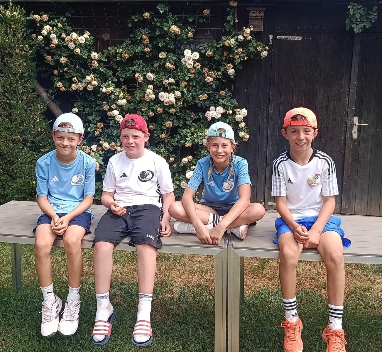 Jungen in Fußballtrikots im Garten am 28. Juni 2026 Vier Jungen in Fußballtrikots sitzen auf einer Bank im Garten, aufgenommen am 28.06.2026