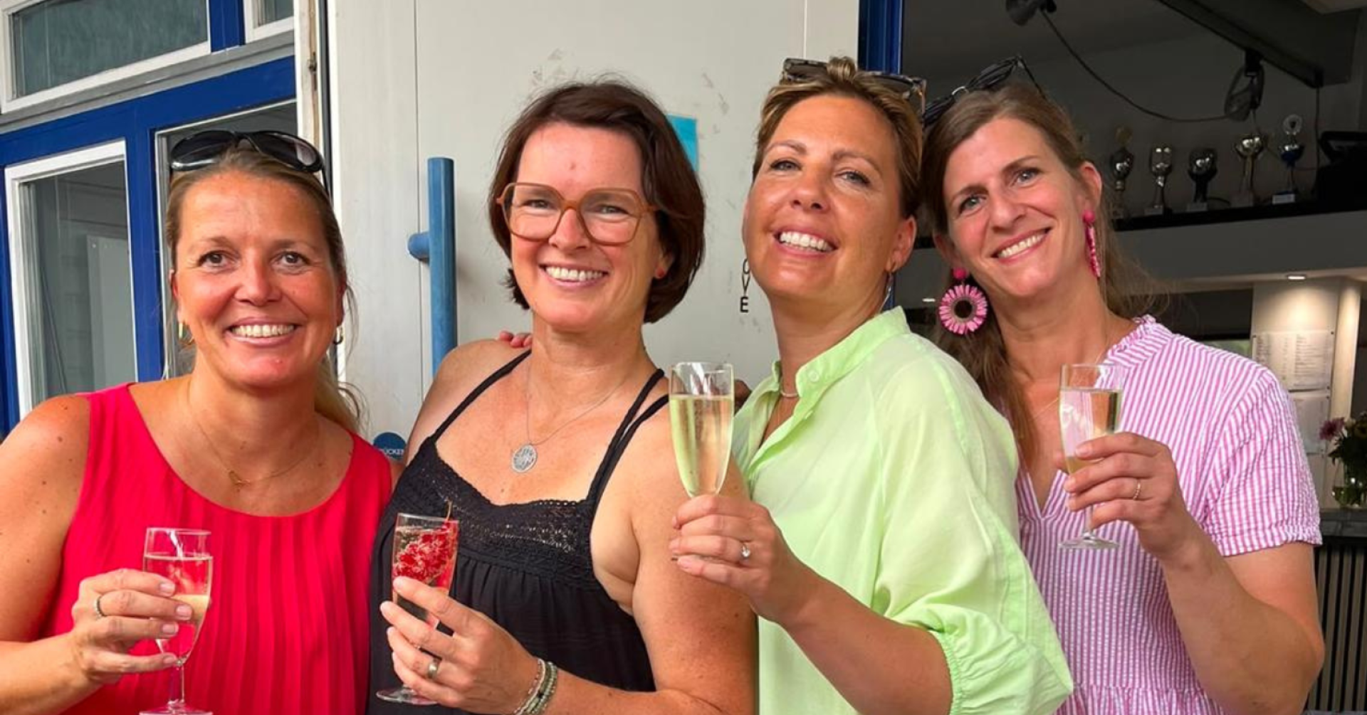 Drei Frauen stoßen beim Sommerfest 2026 mit Sekt an und lächeln fröhlich in die Kamera.