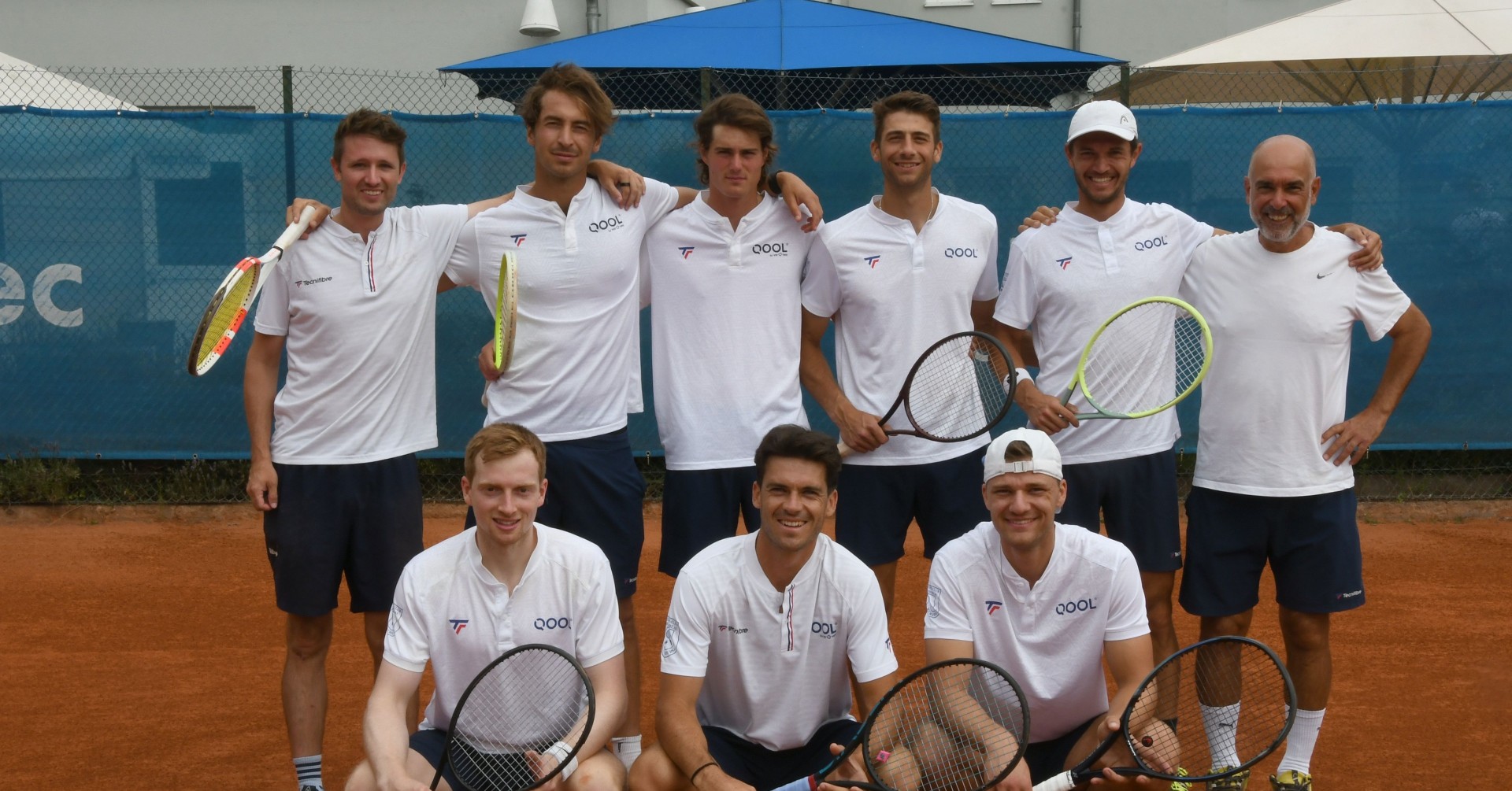 Tennismannschaft posiert für ein Teamfoto auf einem Sandplatz