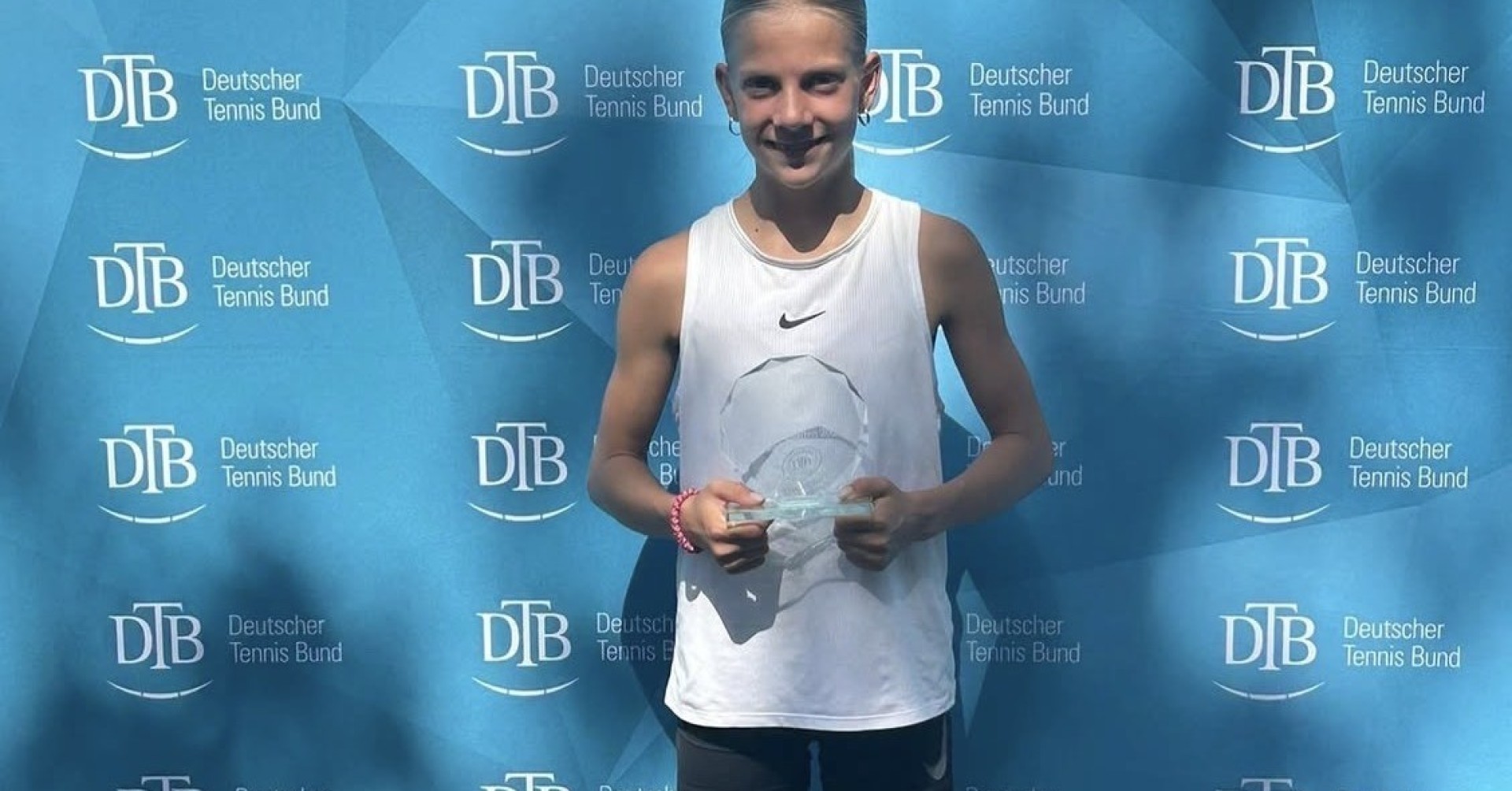 Junges Mädchen mit Pokal vor DTB Deutscher Tennis Bund Hintergrund bei Tennisturnier