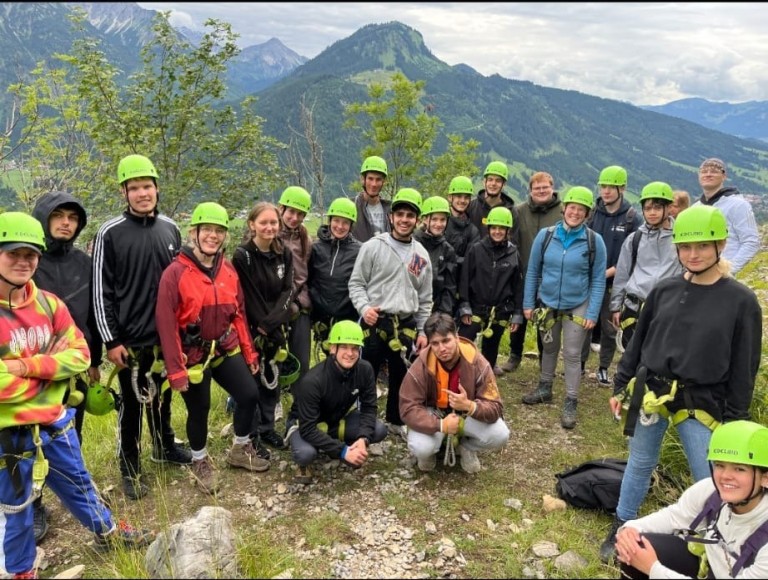Gruppe von Menschen mit grünen Helmen bei einem Abenteuer-Ausflug in den Bergen