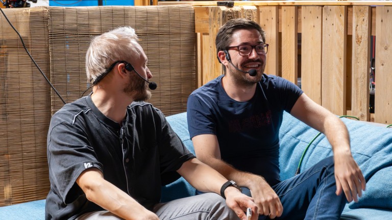 Zwei Männer im Gespräch auf einem Sofa in entspannter Atmosphäre