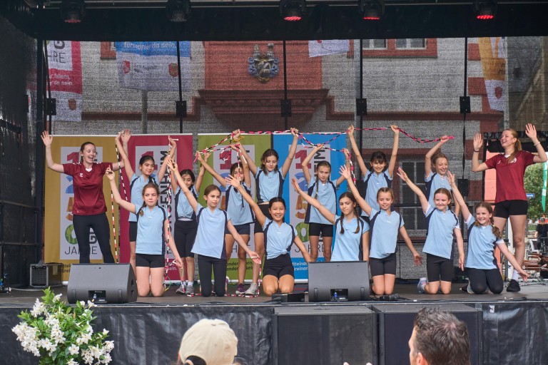 Kinderturngruppe führt auf einer Bühne bei einem Sportevent eine Choreografie auf Kinderturngruppe bei einer Aufführung auf einer Bühne während eines Sportevents