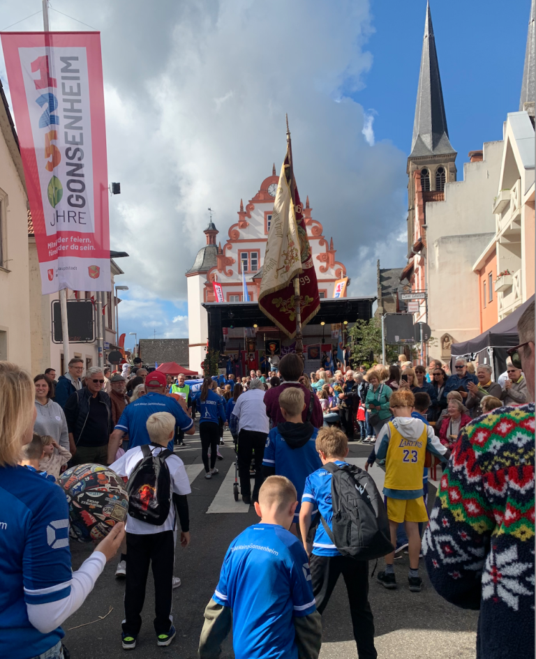 Festumzug in Gonsenheim mit Kindern und Erwachsenen vor dem historischen Rathaus und einer Kirche