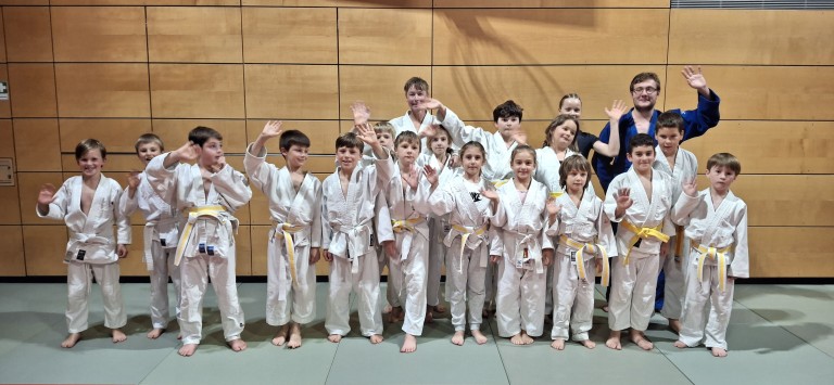 Kinder Judo Gruppe mit weißen Judoanzügen und gelben Gürteln in einer Sporthalle