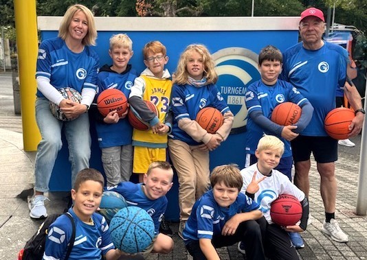 Kinder-Basketballteam der Turngemeinde 1861 mit Basketbällen vor Vereinslogo