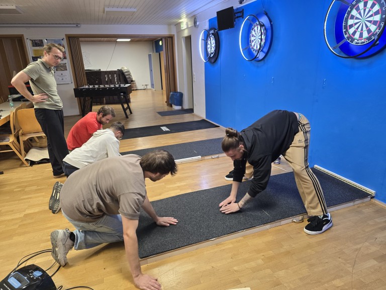 Aufwärmübungen vor dem Dartspiel im Freizeitraum am 27.10.2025 Jugendliche beim Aufwärmen vor einer Dartscheibe in einem Freizeitraum mit Kickertisch