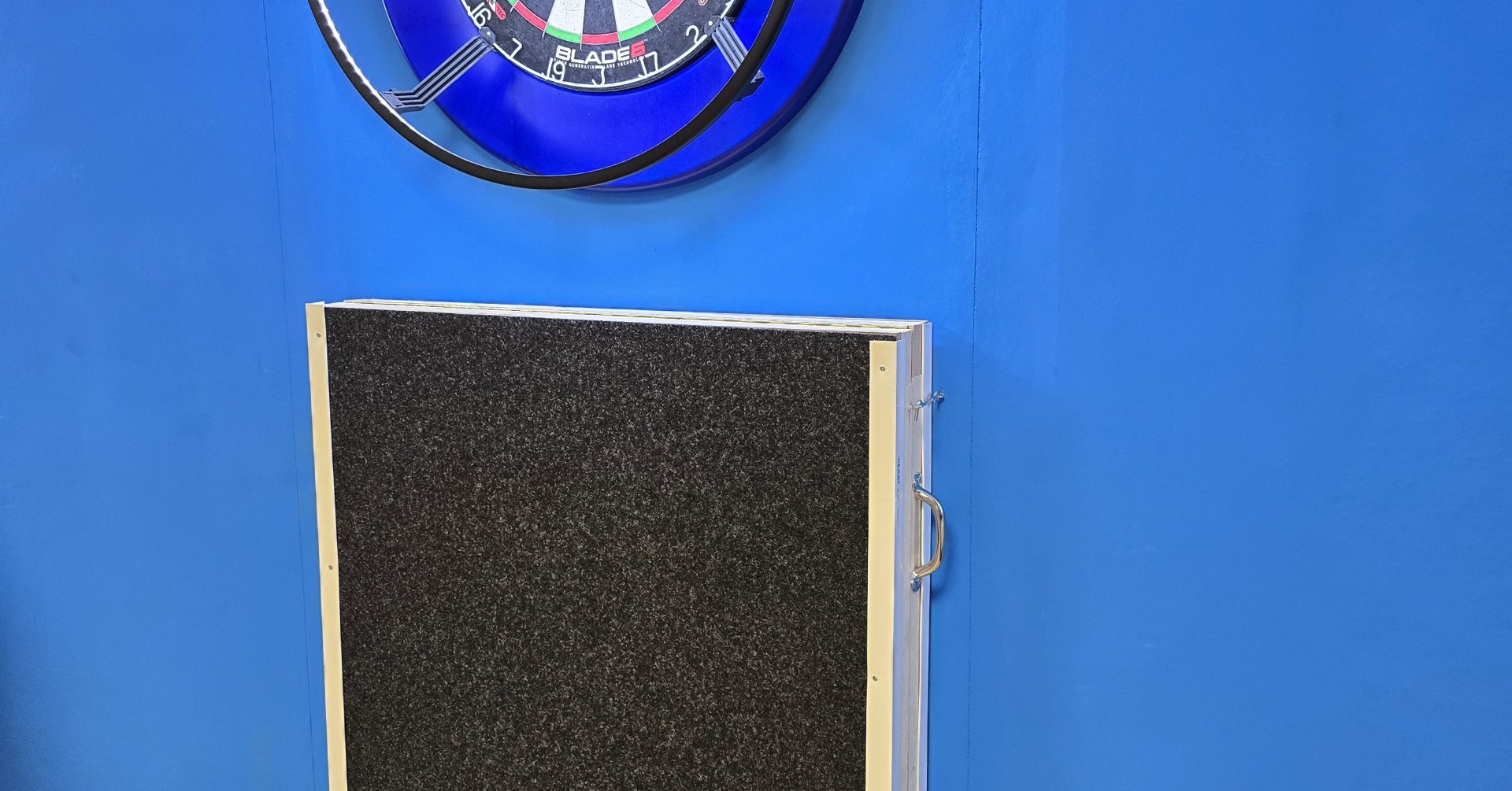 Dartboard Winmau Blade 6 mit Schutzunterlage am 27.10.2025 an blauer Wand Dartboard Winmau Blade 6 an blauer Wand mit Schutzunterlage darunter, aufgenommen am 27.10.2025