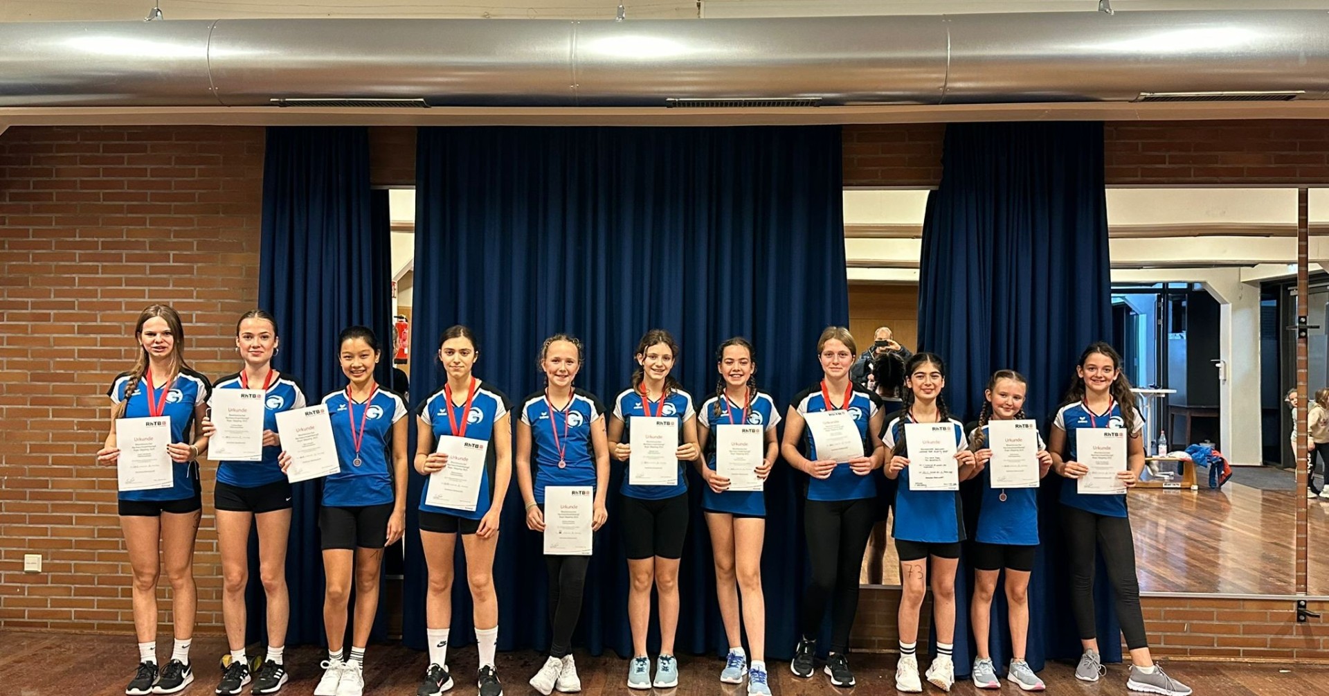 Sportliche Siegerehrung: Mädchenmannschaft mit Urkunden und Medaillen bei einem Wettkampf