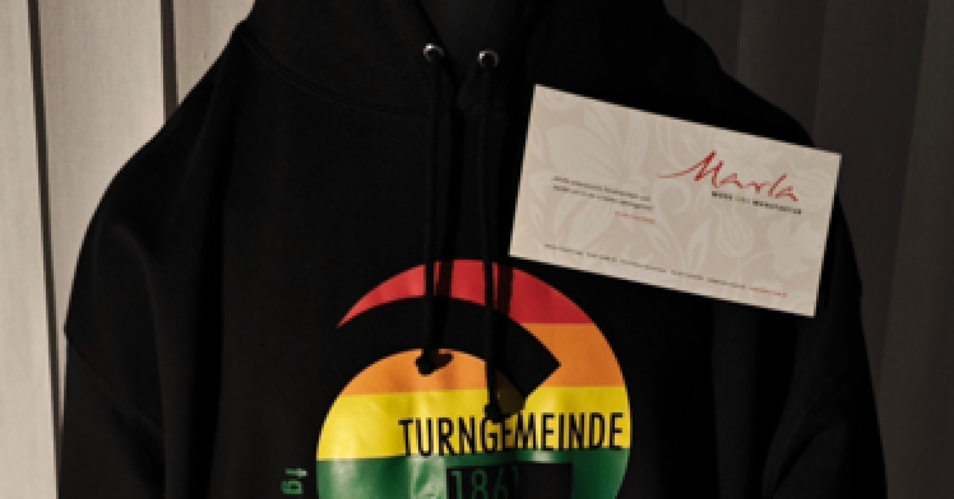 Schwarzer Hoodie mit Regenbogen-Logo der Turngemeinde Gonsenheim, präsentiert von Marla Mode und Manufaktur