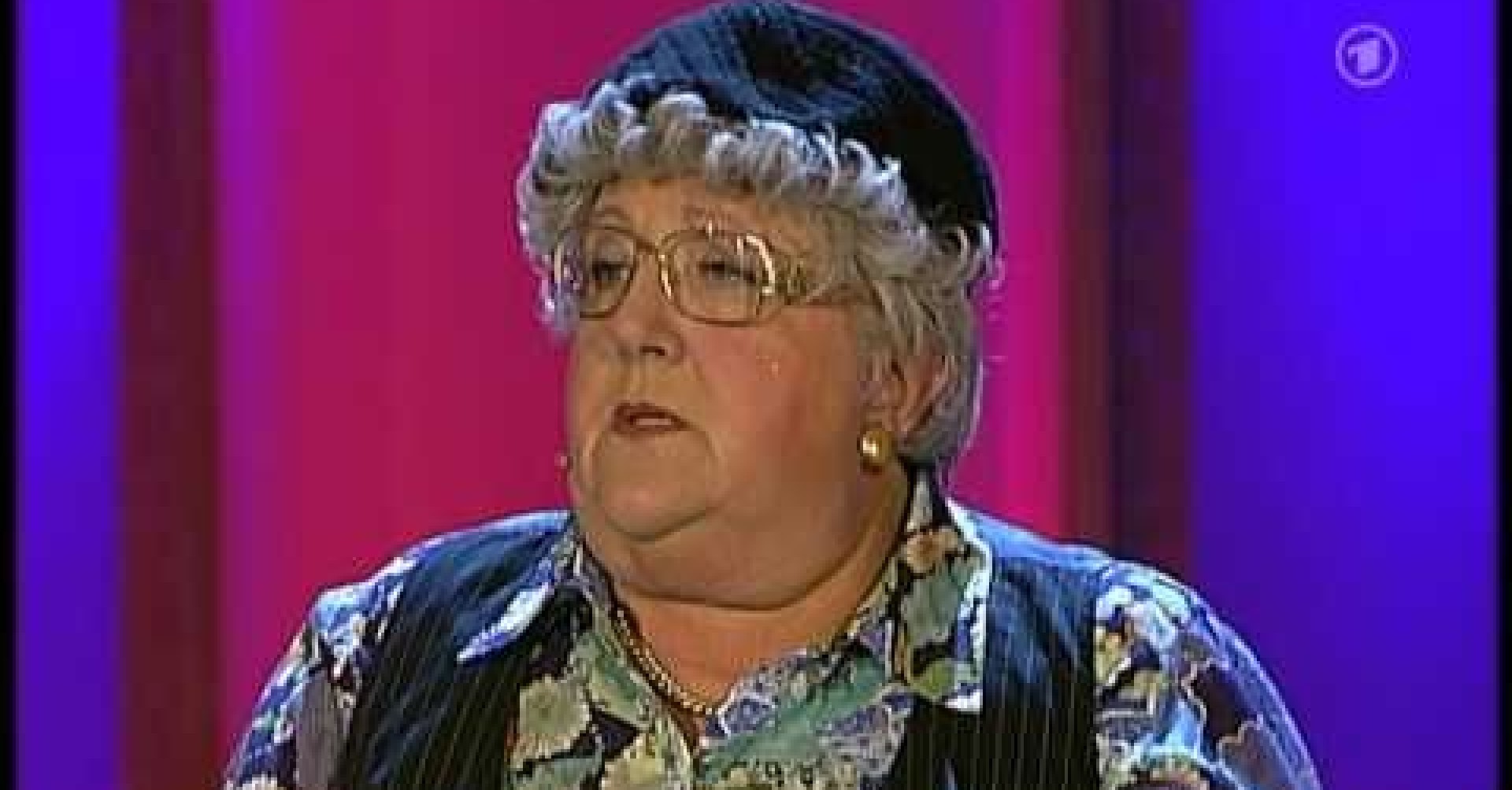 Hildegard auf einer Bühne mit bunter Kleidung und schwarzer Mütze