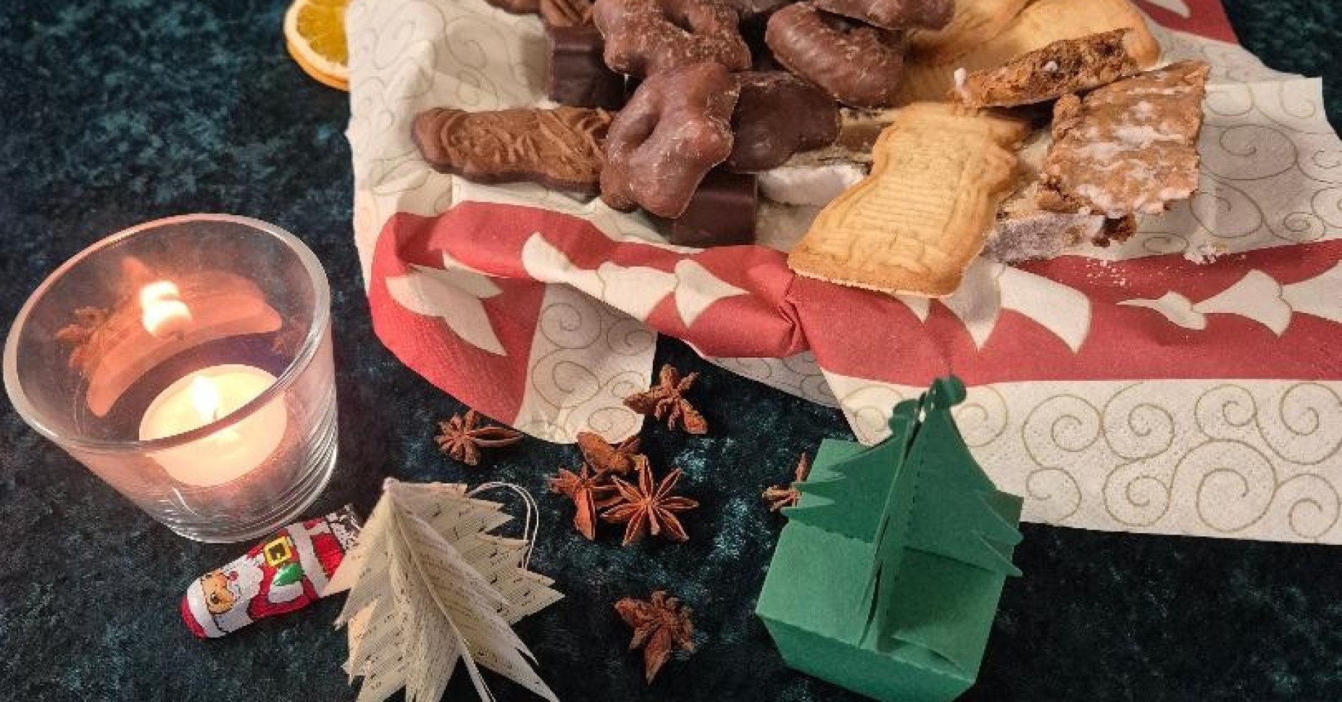 Adventstisch mit Kerze, Weihnachtsgebäck, Spekulatius, Dominosteinen und dekorativen Elementen zur Adventszeit