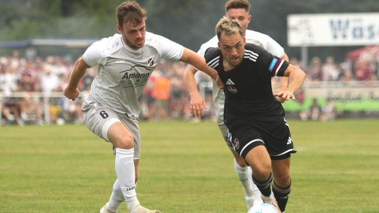 Intensives Fußballspiel mit Spielern im Zweikampf um den Ball Zwei Fußballspieler kämpfen um den Ball während eines Spiels auf einem Rasenplatz.