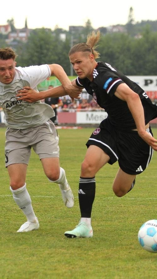 Spannder Zweikampf zwischen zwei Fußballspielern auf dem Spielfeld Zwei Fußballspieler in Aktion während eines Spiels, einer in schwarzem Trikot und der andere in weißem Trikot.