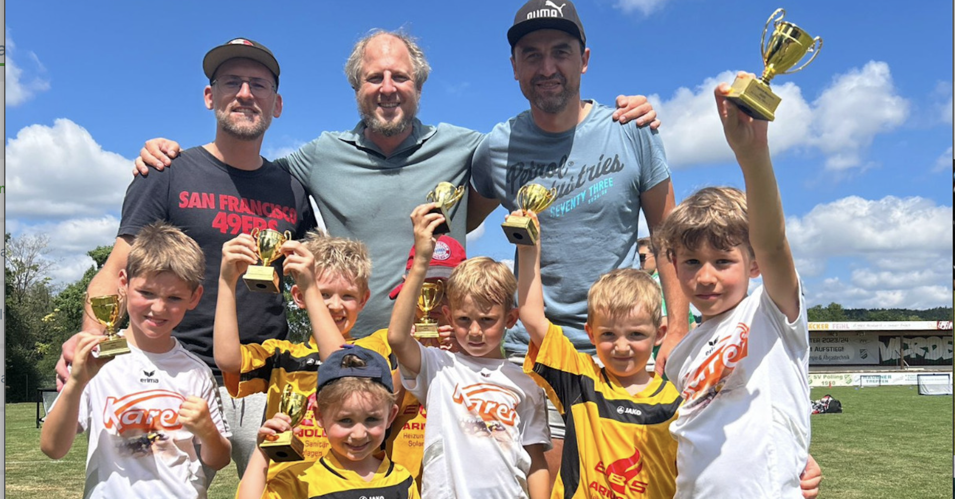 Kinder-Fußballmannschaft mit Trainern hält Pokale nach Turniersieg im Sommer 2025