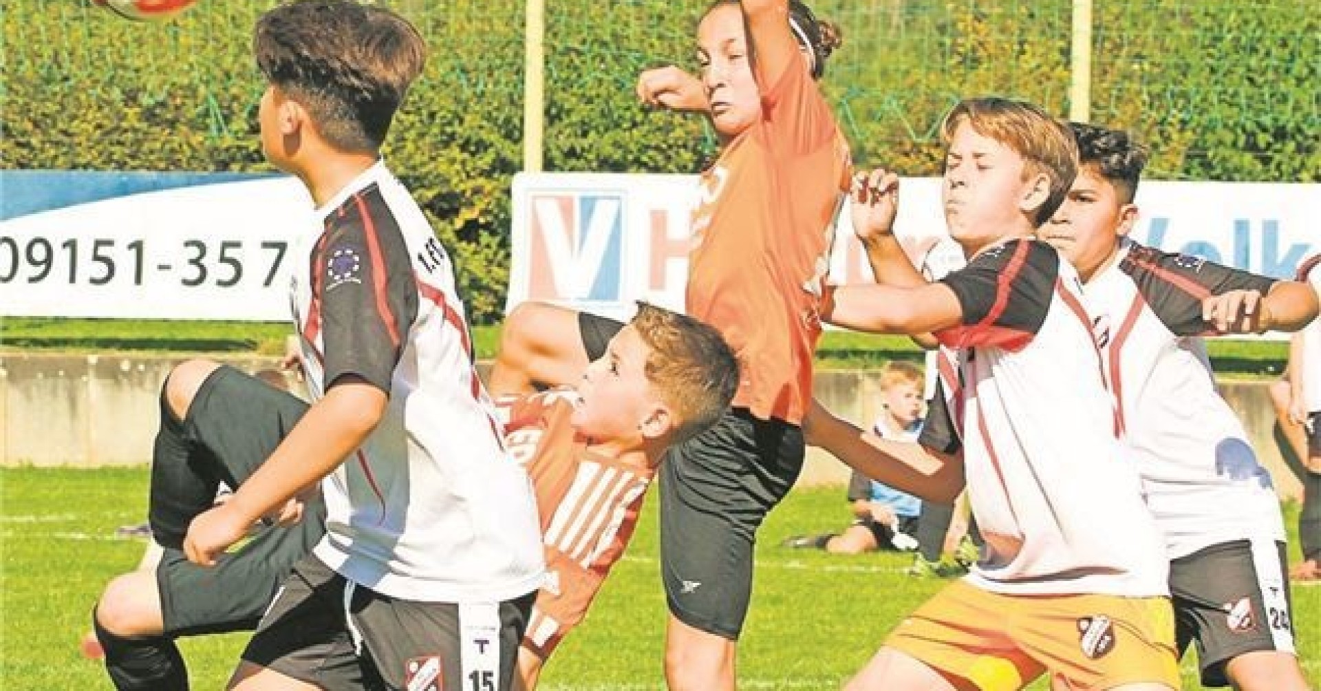 Jugendfußballspiel auf dem Rasen, mehrere junge Spieler kämpfen um den Ball