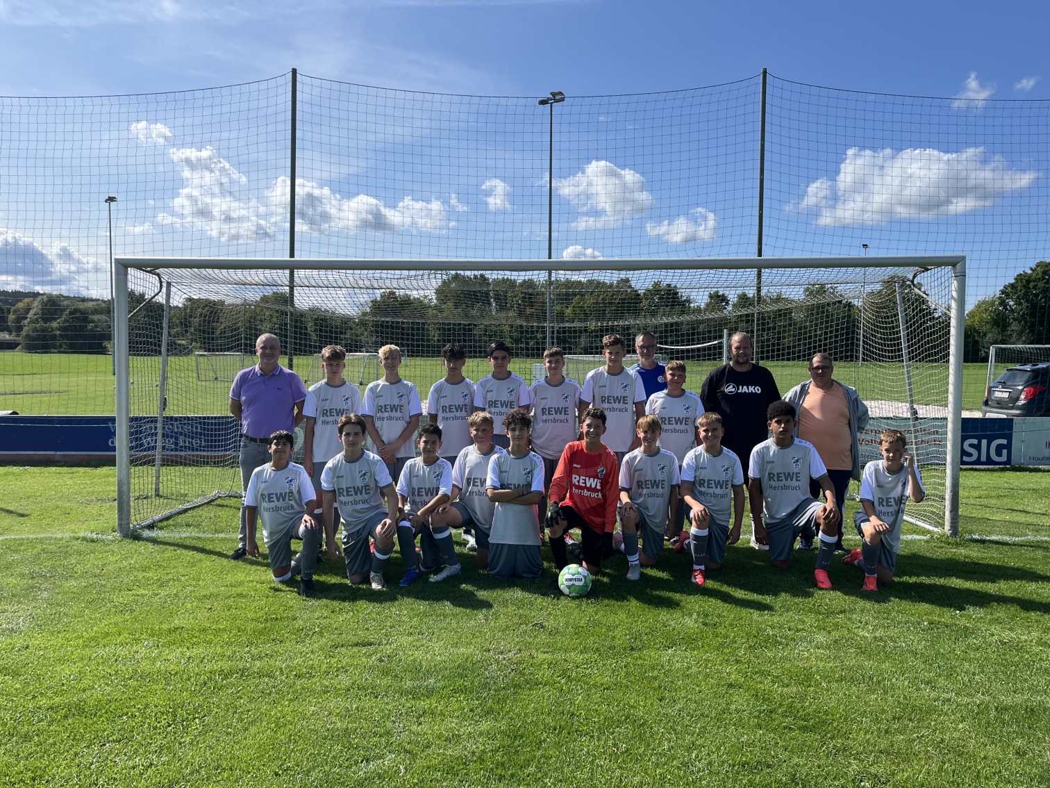 Jugendfußballmannschaft mit REWE Hersbruck Trikots auf dem Sportplatz