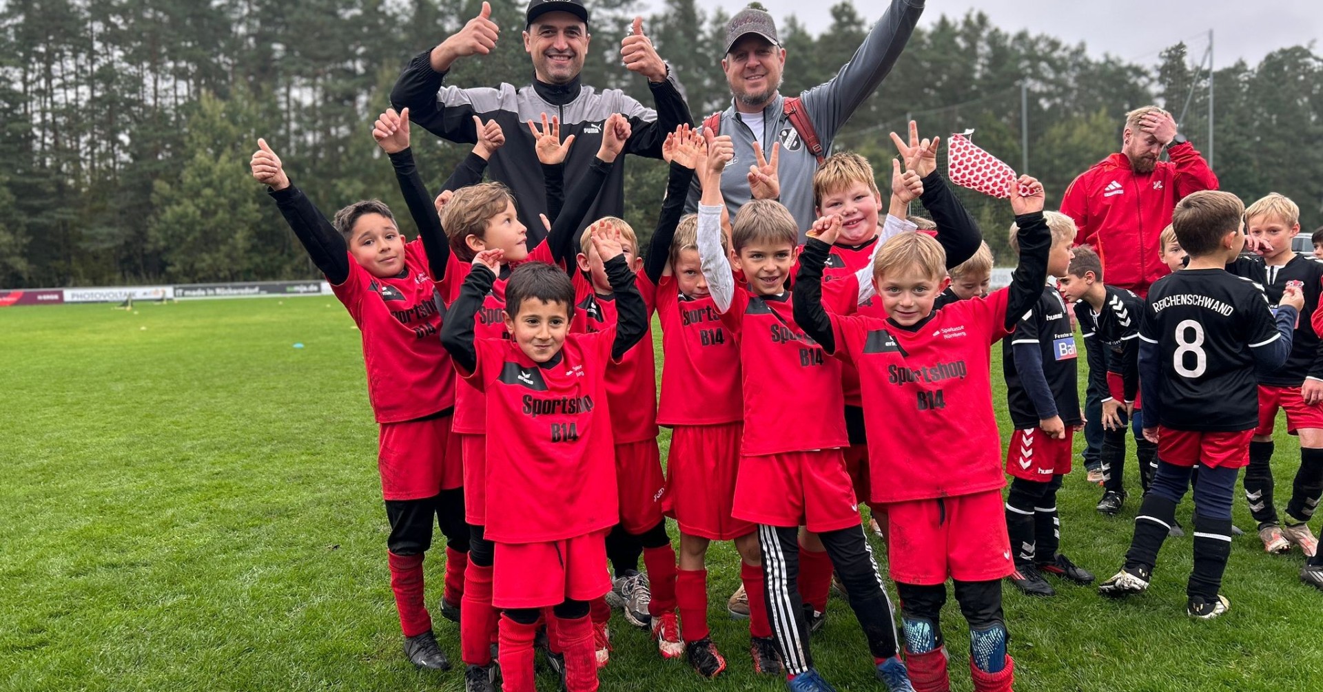 Kinderfußballmannschaft feiert auf dem Sportplatz im Oktober 2025 Kinderfußballmannschaft in roten Trikots jubelt auf dem Sportplatz