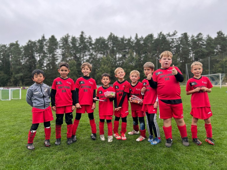 Kinder-Fußballteam mit Sportshop B14 Trikots auf dem Fußballfeld Kinder-Fußballmannschaft in roten Trikots von Sportshop B14 auf dem Fußballplatz