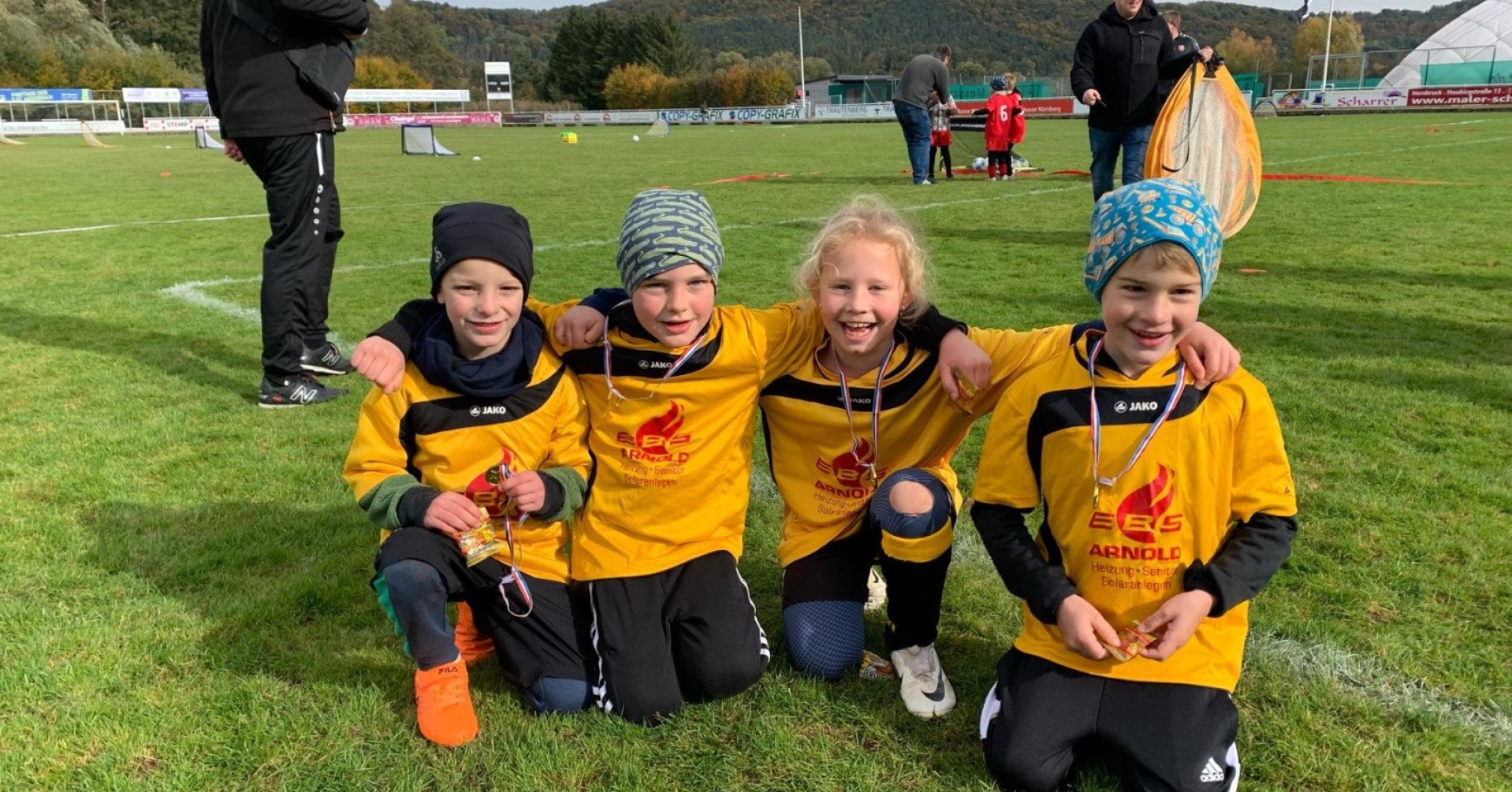 Kinder-Fußballmannschaft beim Jugendturnier mit Medaillen auf dem Sportplatz Kinder-Fußballmannschaft mit gelben Trikots bei einem Jugendturnier auf dem Sportplatz