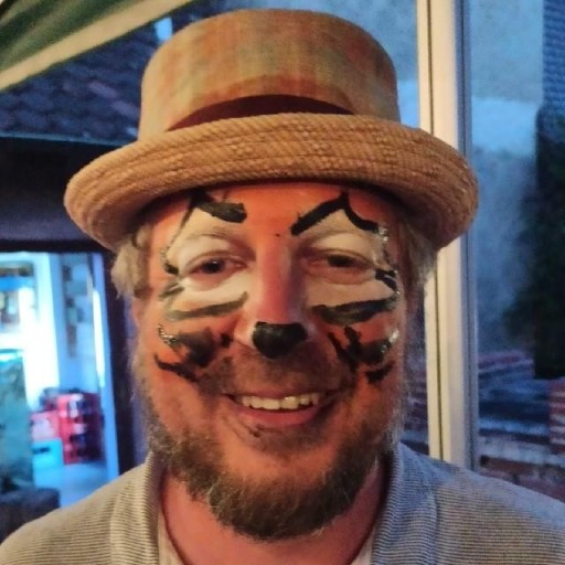 Person mit Strohhut und grauem Bart in einem Innenhof am Abend