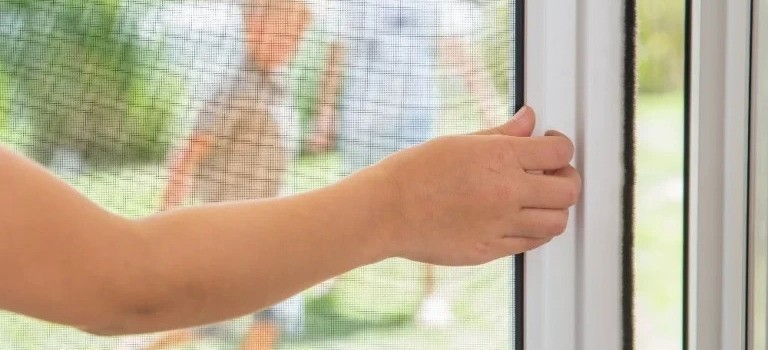 Effektiver Insektenschutz für Fenster in Ingolstadt – Fliegengitter Montage Insektenschutz am Fenster in Ingolstadt – Nahaufnahme einer Hand, die ein Fliegengitter schließt