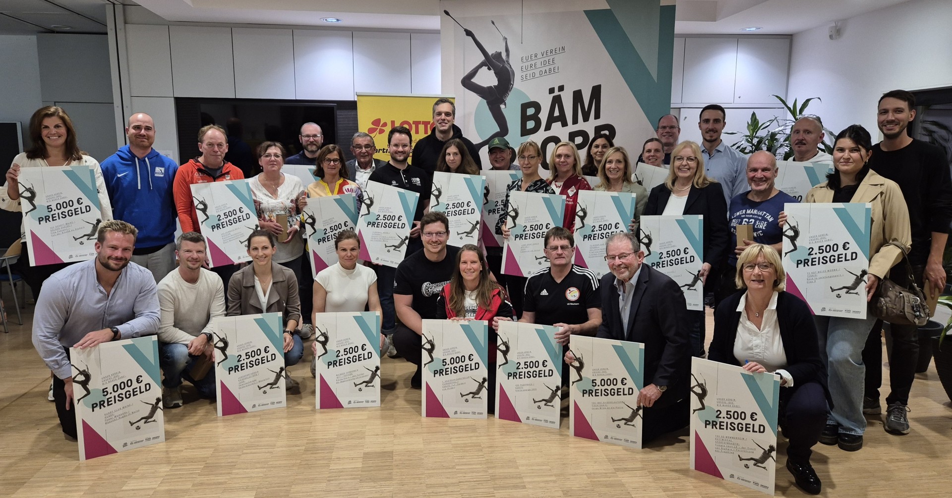 Gruppenfoto bei der BÄM-Award Preisverleihung mit Gewinnern und Preisgeldtafeln