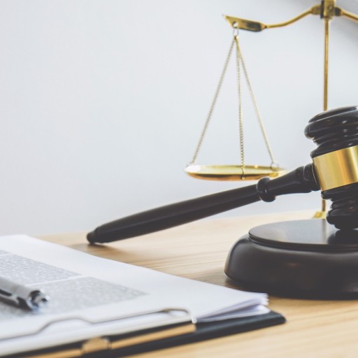 Richterhammer, Gesetzestexte und Waage der Justiz auf einem Schreibtisch, Symbol für Recht und Gerechtigkeit