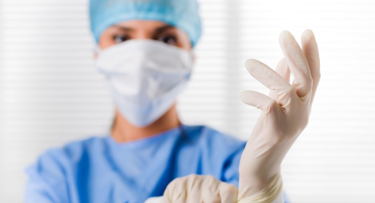 Tastuntersuchung zur Früherkennung von Prostatakrebs vor dem Aus Prostata Hilfe Deutschland: Ärztin zieht sich Handschuhe an