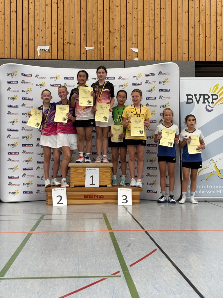 Siegerehrung Badmintonturnier BVRP – Podest mit Urkunden und Medaillen Siegerehrung beim Badmintonturnier des BVRP mit jungen Spielerinnen auf dem Podest, Urkunden und Medaillen in einer Sporthalle