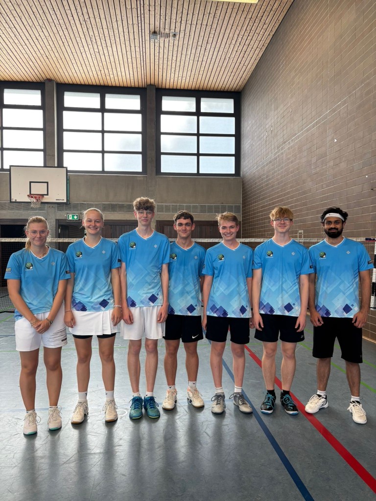 Badmintonteam in blauen Trikots in der Sporthalle Jugendliche Badmintonmannschaft in blauen Trikots in einer Sporthalle