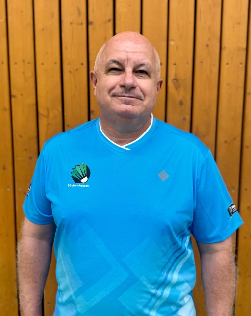 Person im SG Rheinhessen Trikot vor Holzwand