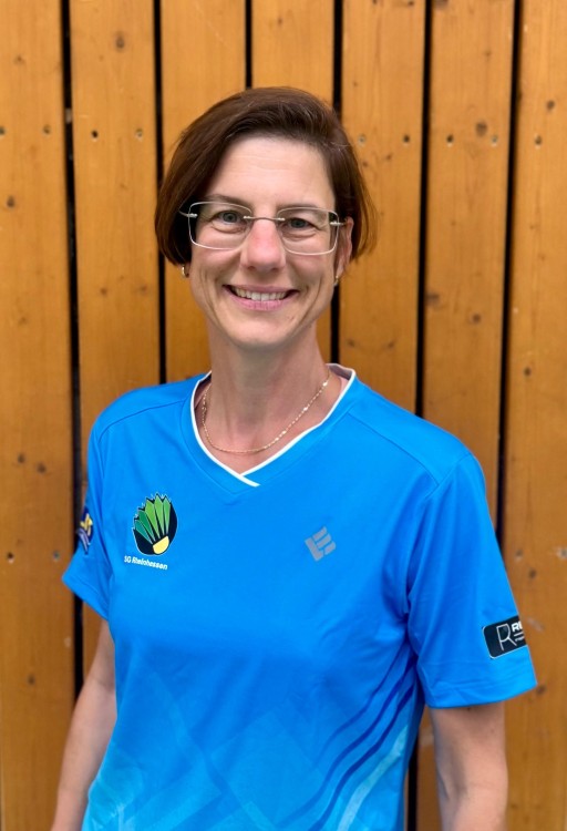 Person im blauen SG Rheinhessen Trikot vor einer Holzwand