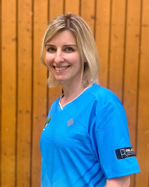 Daria Kurilko im blauen Sporttrikot vor einer Holzwand