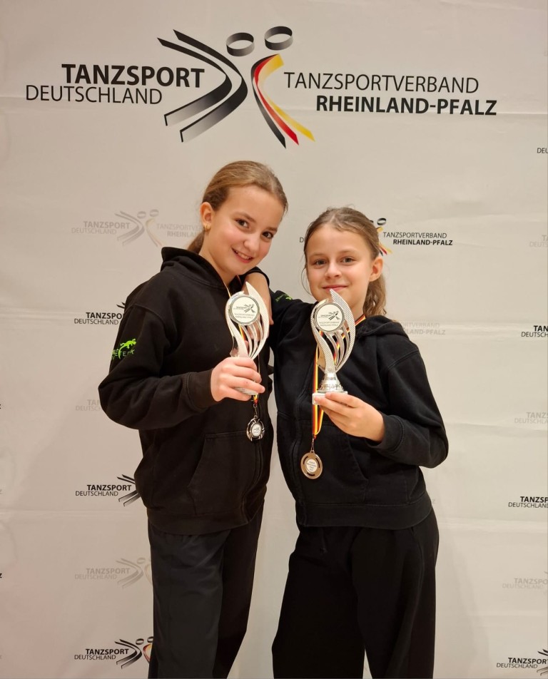 Zwei junge Tänzerinnen mit Pokalen bei einer Siegerehrung des Tanzsportverbands Rheinland-Pfalz