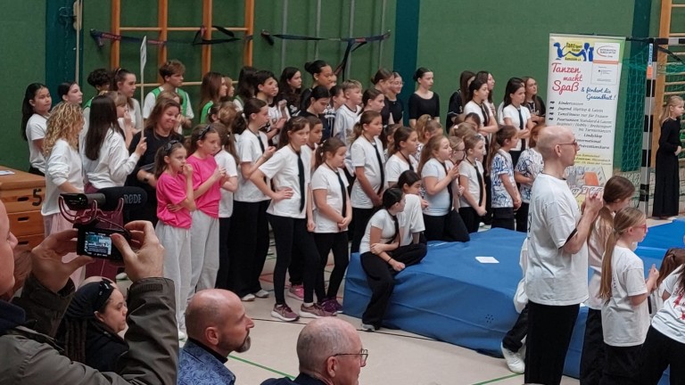 Kinder und Jugendliche bei einer Sportveranstaltung in einer Turnhalle, Gruppen in Sportkleidung