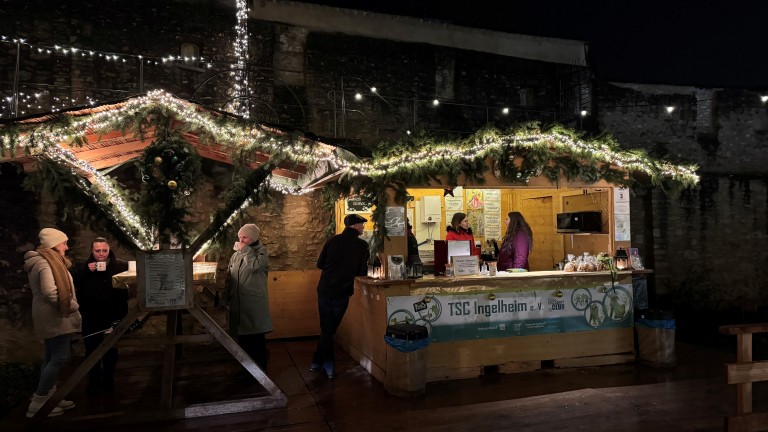 Weihnachtsmarkt mit festlich geschmücktem Stand des TSC Ingelheim e. V. am Abend
