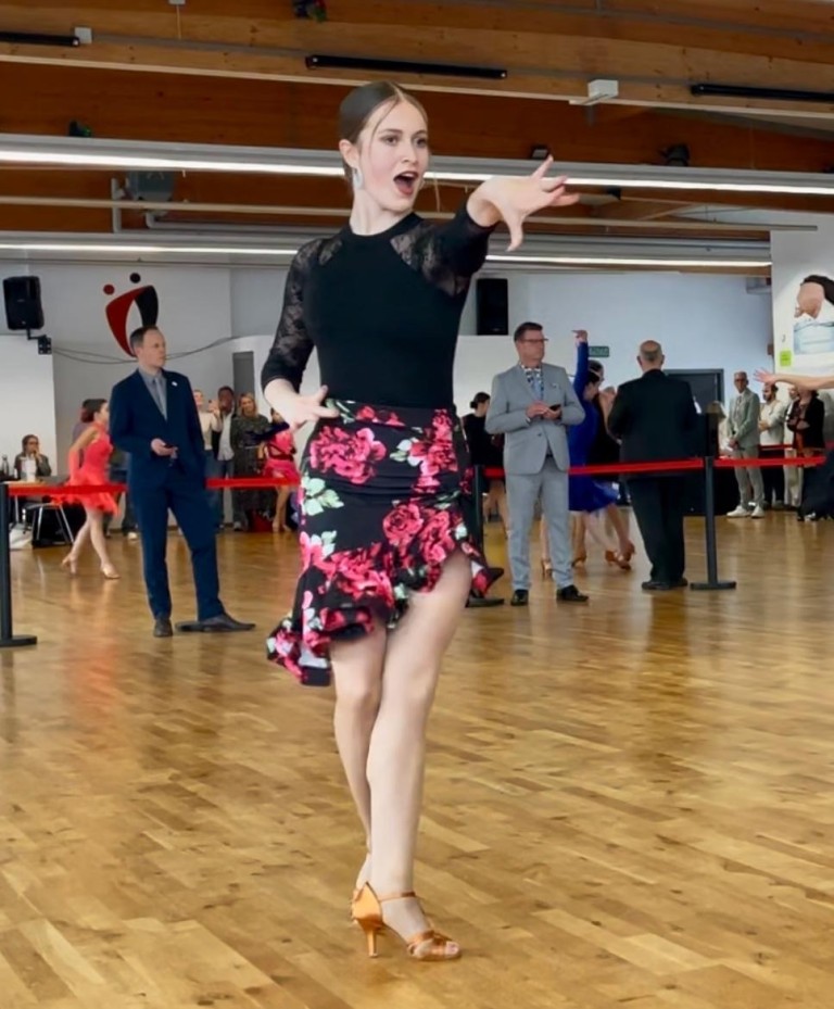 Tänzerin bei Solo-Tanzwettbewerb auf Parkett mit Blumenkleid