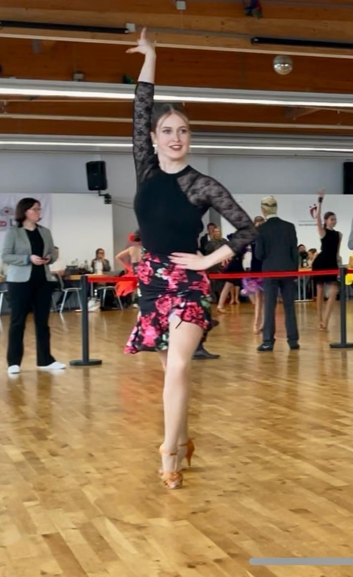 Solotanz auf Turnierparkett mit eleganter Tanzkleidung und Blumenmuster