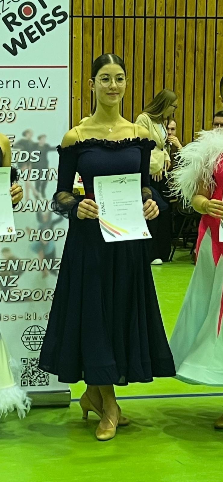 Siegerin bei einem Tanzturnier mit Urkunde im eleganten Kleid