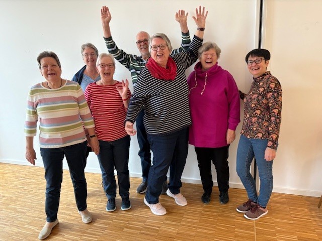 Gruppe älterer Menschen beim Seniorentanz in einem hellen Raum
