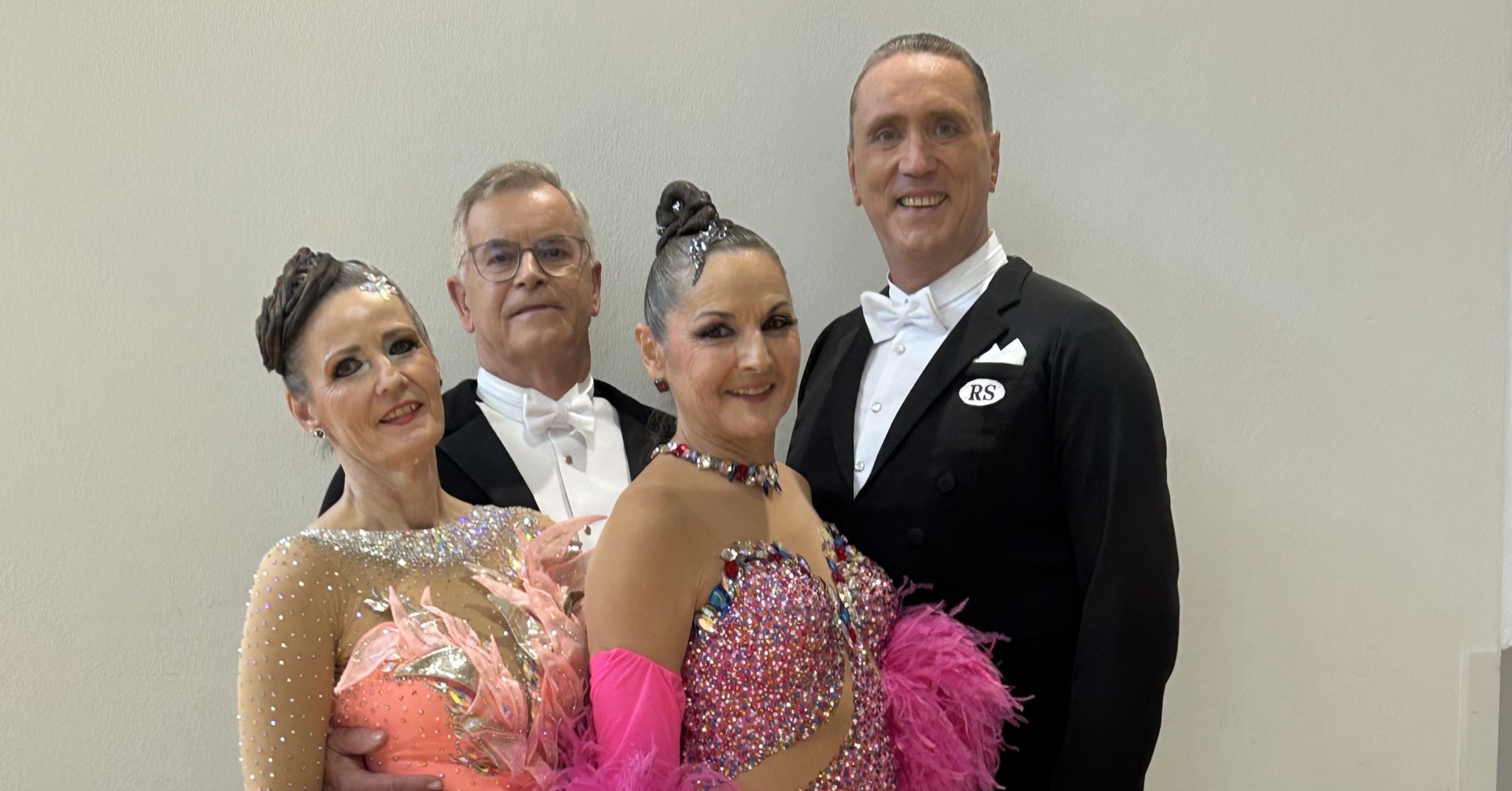 Tanzpaar in festlicher Turnierkleidung bei einem Tanzwettbewerb, Herren im Frack und Damen in glitzernden Kleidern mit Federn