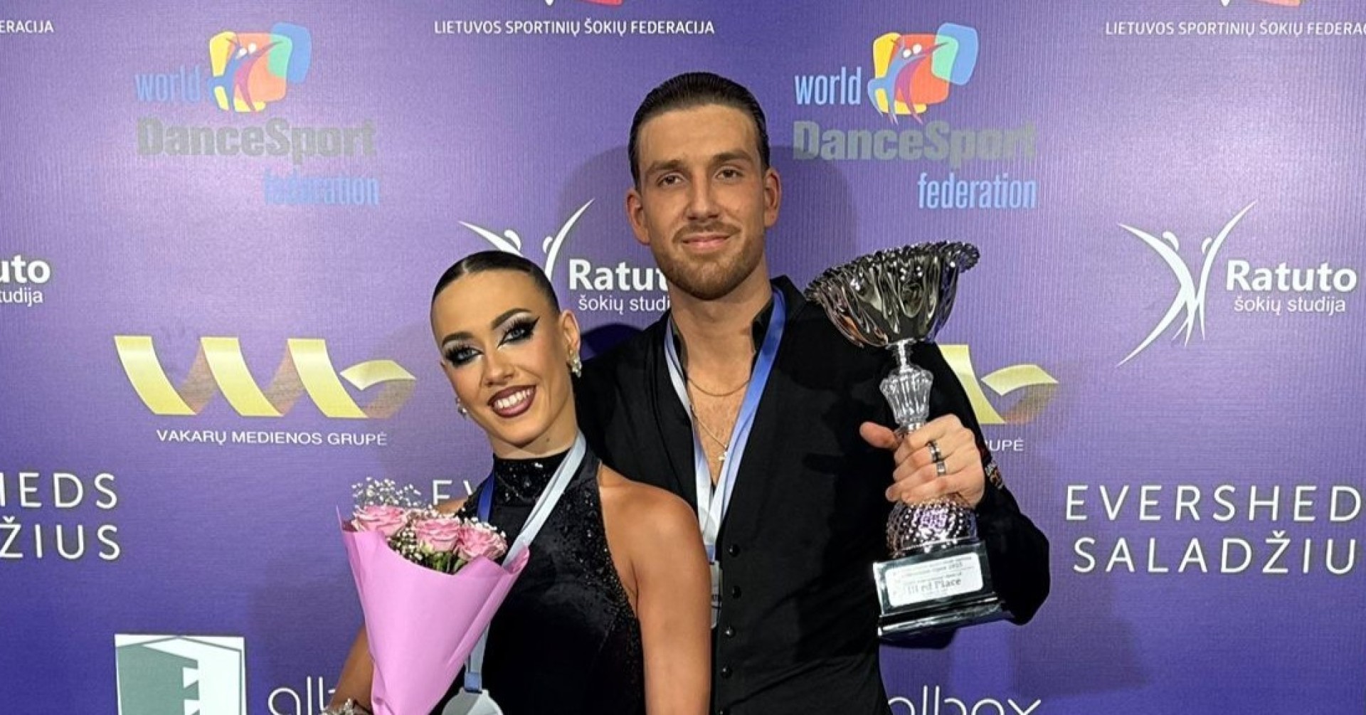 Justin Lauer und Rita Schumichin mit Pokal bei einem Tanzsport-Wettbewerb der World DanceSport Federation