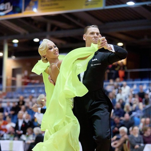Elegantes Paar bei einem Tanzturnier in leuchtendem Tanzkleid Elegantes Tanzpaar in lebhaftem Tanzkleid bei einem Tanzturnier