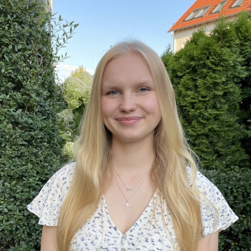 Porträt einer jungen Frau im Garten Junge Frau mit blonden Haaren lächelt im Garten