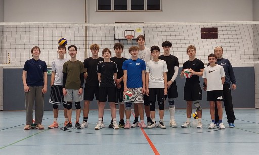 Volleyball Jugendmannschaft mit Andreas in der Sporthalle vor dem Netz
